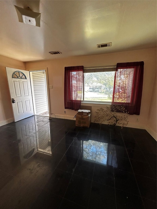 entrance foyer featuring dark tile patterned floors, visible vents, and baseboards