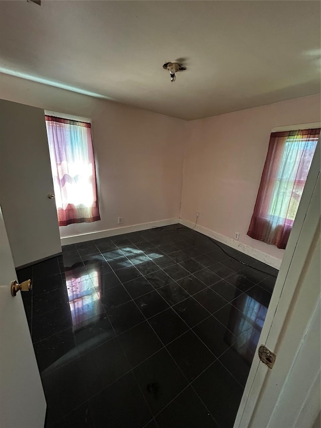 spare room with a wealth of natural light and baseboards