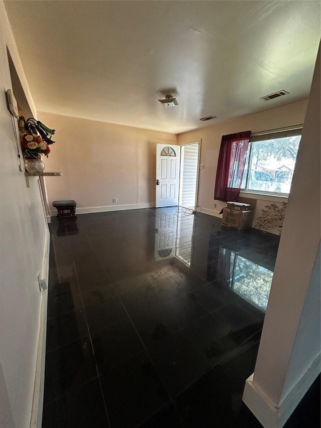 hall with baseboards, visible vents, and tile patterned floors