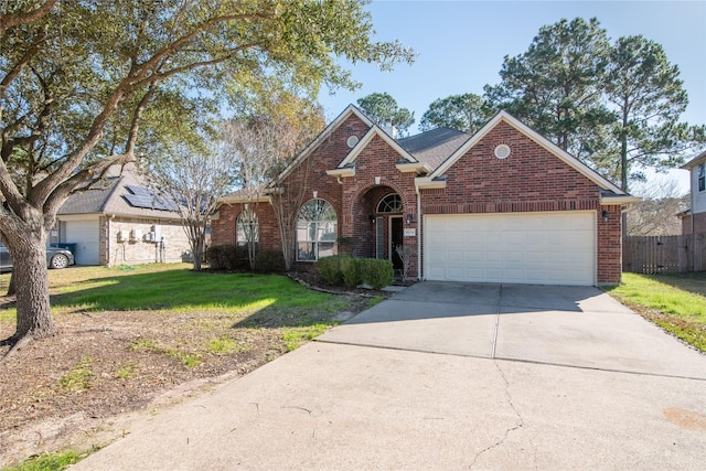 view of front of property featuring an attached garage, brick siding, fence, concrete driveway, and a front yard