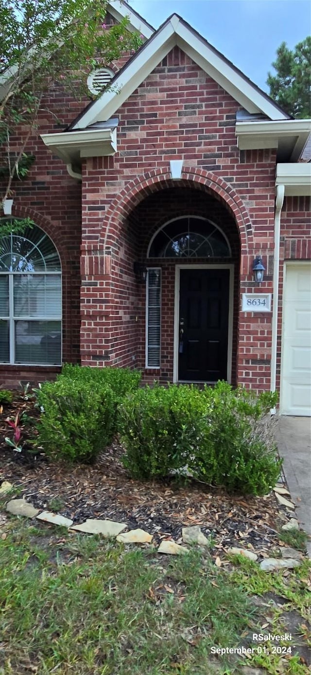 property entrance featuring an attached garage and brick siding