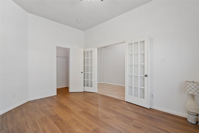 spare room with french doors, wood finished floors, and baseboards