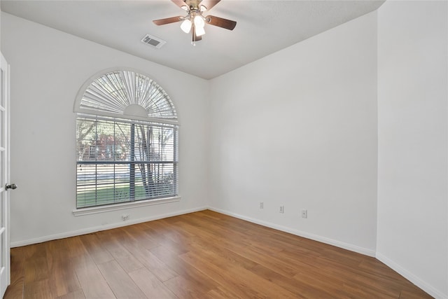 spare room featuring ceiling fan, wood finished floors, visible vents, and baseboards