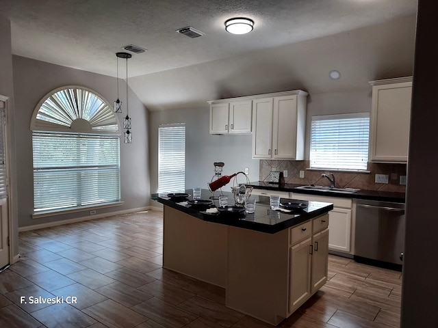 kitchen featuring dark countertops, lofted ceiling, visible vents, a sink, and dishwasher