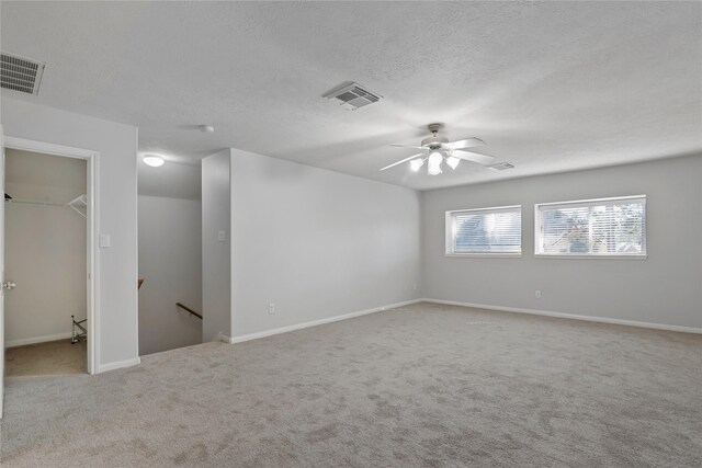 spare room with carpet, visible vents, and a textured ceiling