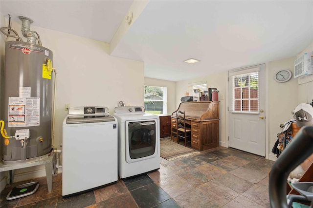 washroom with water heater, stone finish flooring, washer and dryer, laundry area, and a wall mounted air conditioner