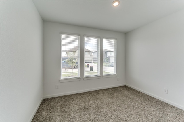 carpeted empty room featuring baseboards