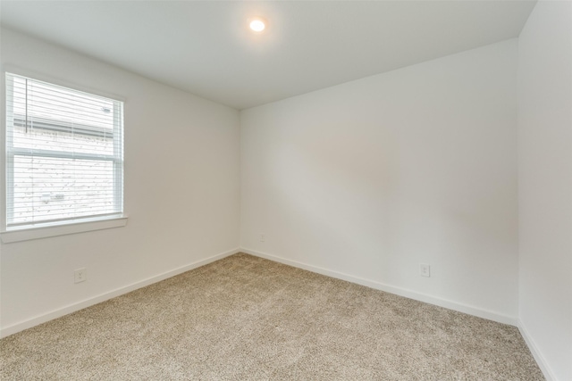 empty room featuring light carpet and baseboards