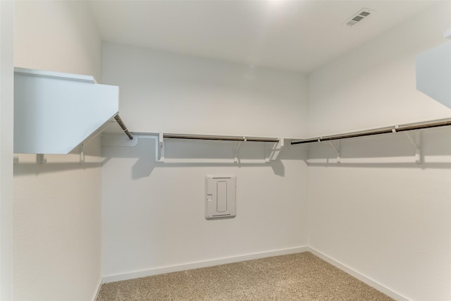 walk in closet with light colored carpet, visible vents, and electric panel