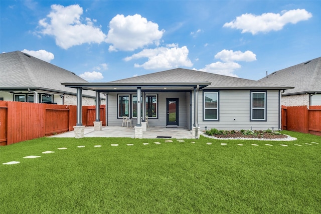 back of house featuring a yard, a shingled roof, a patio, and a fenced backyard