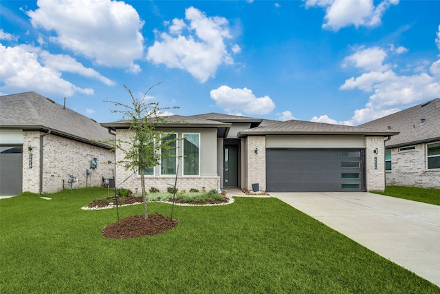 prairie-style home featuring brick siding, roof with shingles, concrete driveway, a garage, and a front lawn