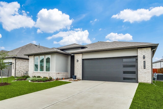 prairie-style house featuring concrete driveway, brick siding, a front lawn, and an attached garage