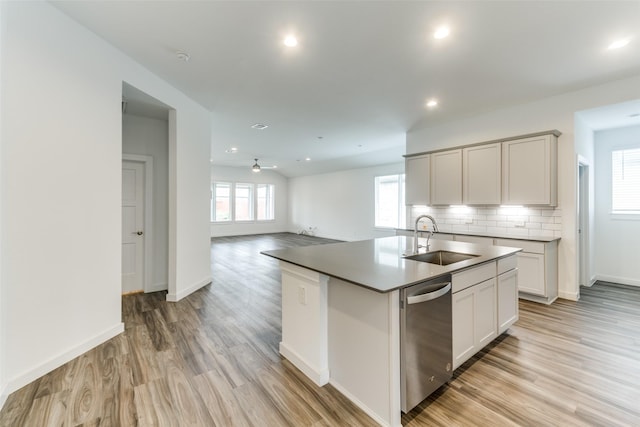 kitchen featuring light wood-style floors, dishwasher, backsplash, and a sink