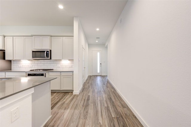 kitchen with tasteful backsplash, baseboards, appliances with stainless steel finishes, light wood-style floors, and recessed lighting