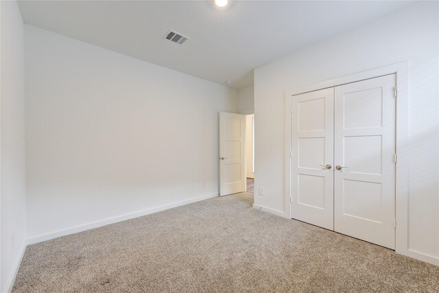 unfurnished bedroom featuring a closet, carpet flooring, visible vents, and baseboards