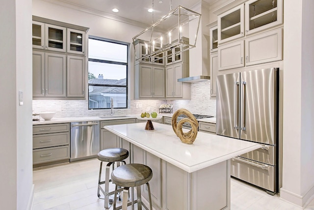 kitchen with gray cabinetry, stainless steel appliances, a sink, light countertops, and a center island