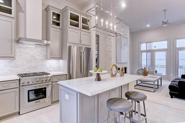 kitchen with wall chimney exhaust hood, appliances with stainless steel finishes, backsplash, and light countertops