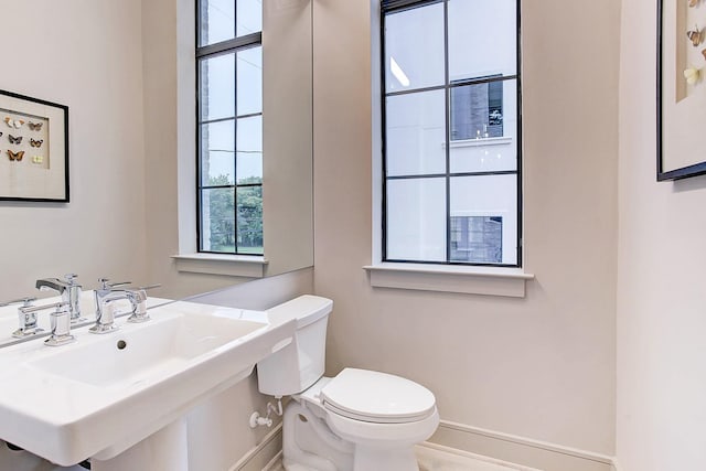 bathroom featuring a sink, toilet, and baseboards