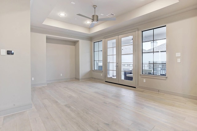 spare room featuring light wood-style flooring, visible vents, a ceiling fan, french doors, and a raised ceiling