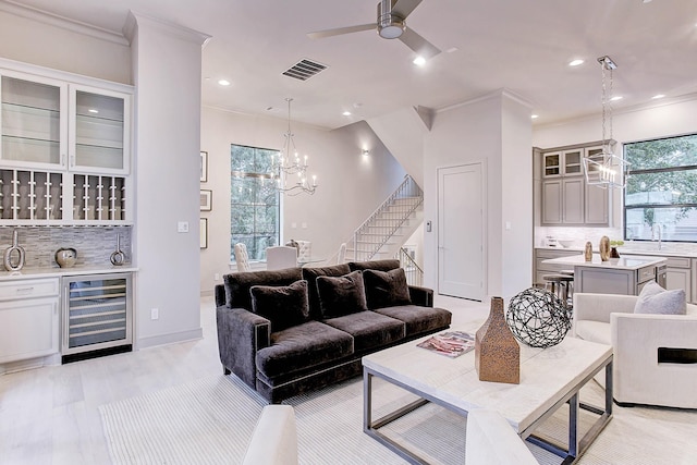 living area featuring beverage cooler, visible vents, ornamental molding, stairs, and recessed lighting