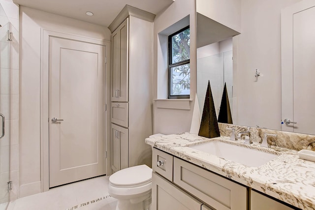 bathroom with tile patterned flooring, tiled shower, vanity, and toilet