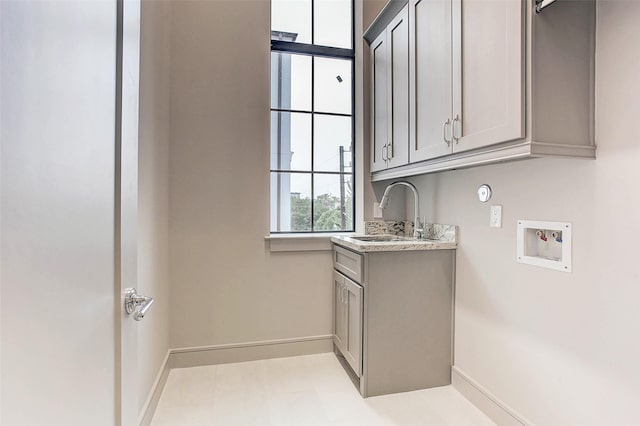 clothes washing area featuring hookup for a washing machine, cabinet space, baseboards, and a sink