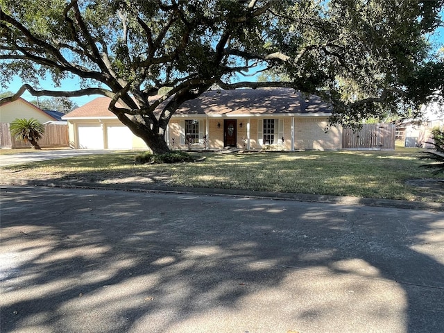 single story home featuring a garage, brick siding, fence, concrete driveway, and a front lawn