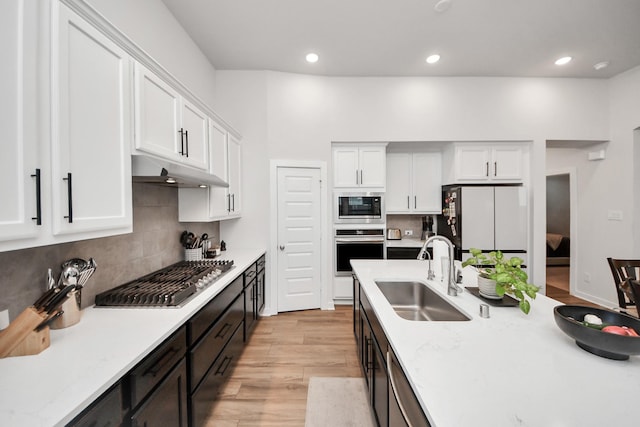 kitchen featuring appliances with stainless steel finishes, a sink, white cabinetry, and under cabinet range hood