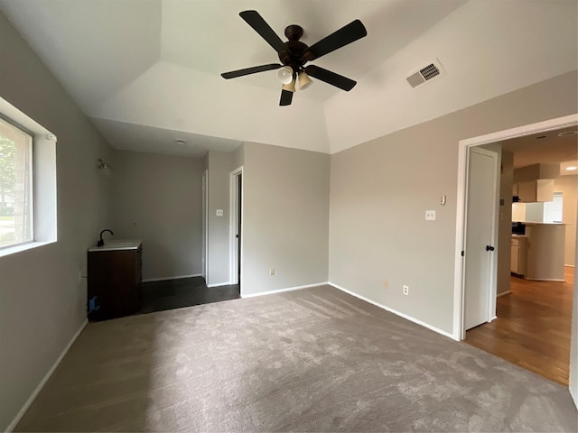 interior space with baseboards, visible vents, lofted ceiling, ceiling fan, and a sink