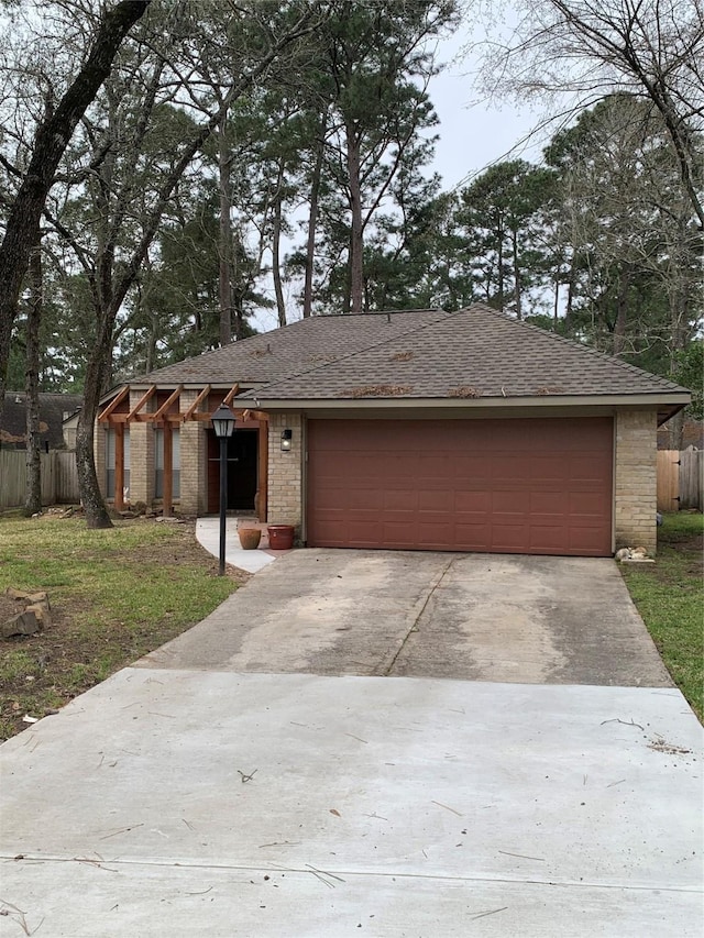 view of front of home featuring a garage, driveway, a shingled roof, and fence