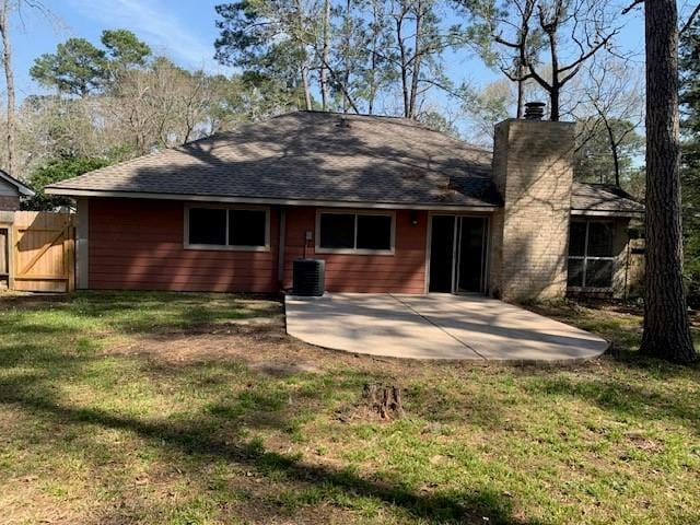 rear view of property featuring a patio, a yard, central AC, and a chimney