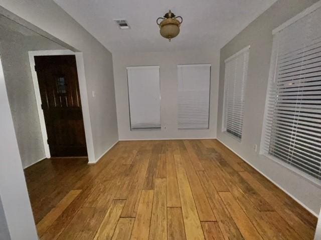 unfurnished room with visible vents and hardwood / wood-style flooring