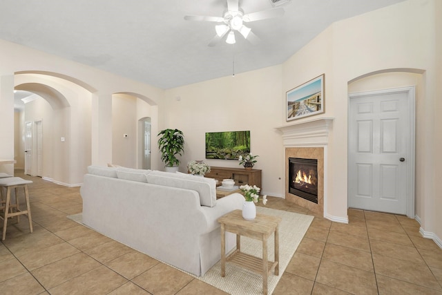 living room with light tile patterned floors, ceiling fan, a fireplace, and baseboards