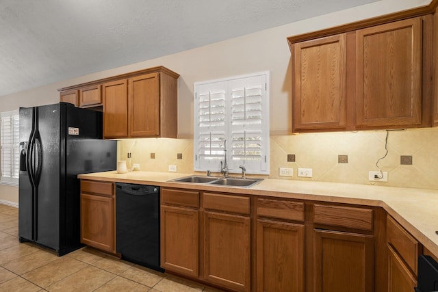 kitchen with a sink, black appliances, brown cabinets, and light countertops