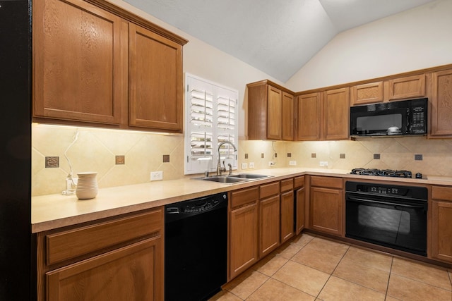 kitchen featuring lofted ceiling, black appliances, brown cabinetry, and a sink