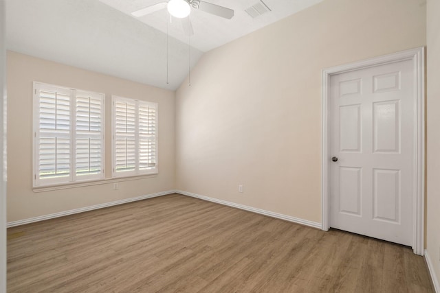 spare room featuring visible vents, baseboards, vaulted ceiling, a ceiling fan, and light wood-type flooring