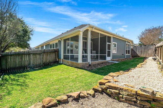 rear view of house with a lawn, a fenced backyard, and a sunroom