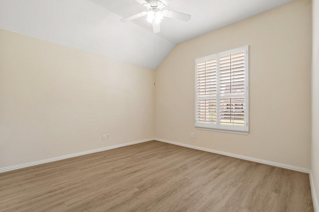 empty room featuring lofted ceiling, ceiling fan, baseboards, and wood finished floors