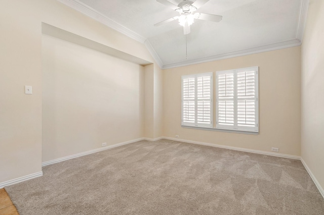 carpeted empty room featuring lofted ceiling, crown molding, baseboards, and ceiling fan