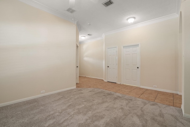 carpeted empty room with tile patterned flooring, visible vents, crown molding, and baseboards