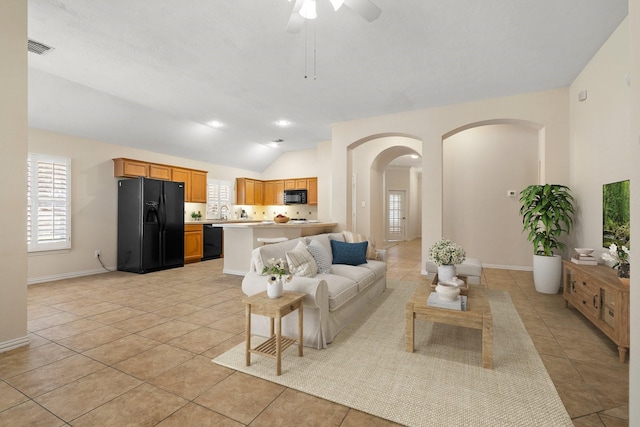 living room with arched walkways, lofted ceiling, visible vents, light tile patterned flooring, and baseboards