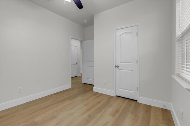 unfurnished bedroom featuring a ceiling fan, light wood-style flooring, and baseboards