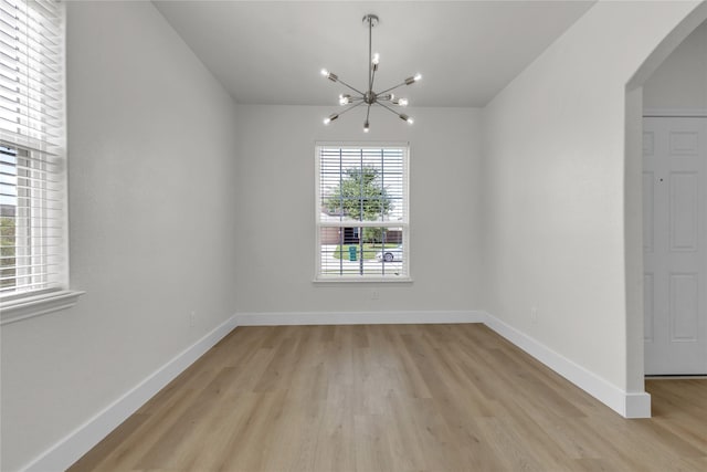 unfurnished dining area with baseboards, light wood-style floors, and a notable chandelier