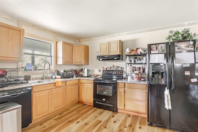 kitchen with light brown cabinets, a sink, light wood-type flooring, under cabinet range hood, and black appliances