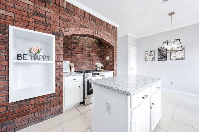 kitchen featuring gas stove, crown molding, brick wall, and light tile patterned floors