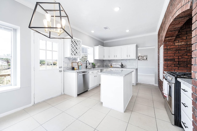 kitchen with tasteful backsplash, white cabinets, appliances with stainless steel finishes, ornamental molding, and a sink