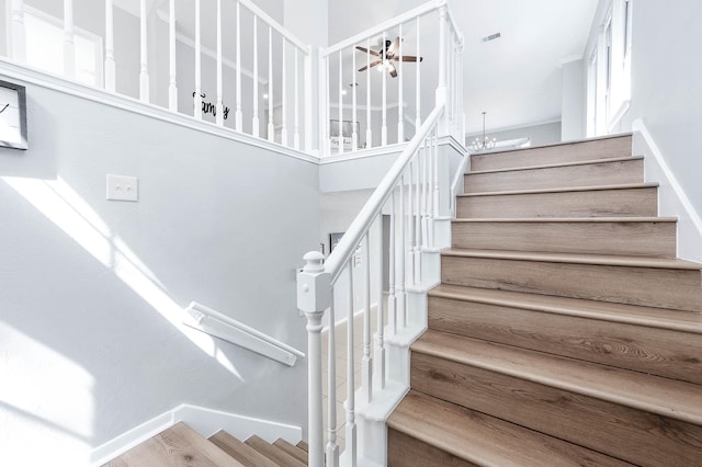 stairs with ceiling fan and baseboards