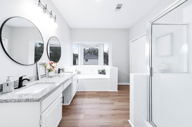 full bathroom featuring wood finished floors, a sink, visible vents, and a shower stall