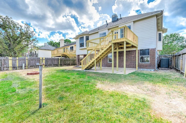 rear view of house featuring a fenced backyard, brick siding, stairs, a wooden deck, and a patio area