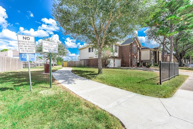 view of community featuring an attached garage, fence, and a yard